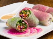 White plate with spring rolls and pink sauce.