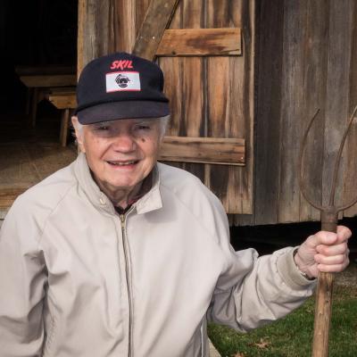 Picture of Lee Bassett with baseball hat and pitchfork. 